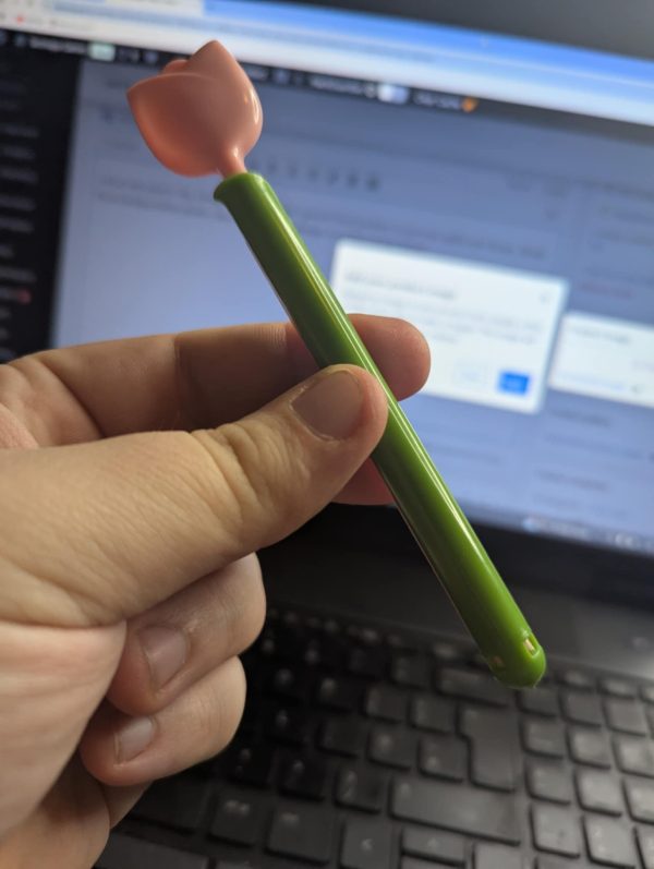 The Pink and Green flower pin is being held in the hand of a man.